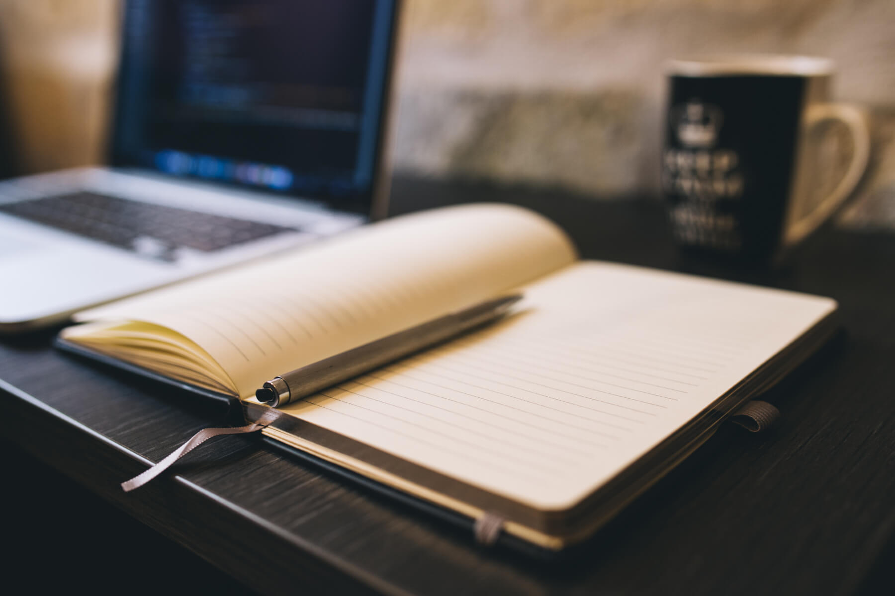 laptop with a notebook and a mug